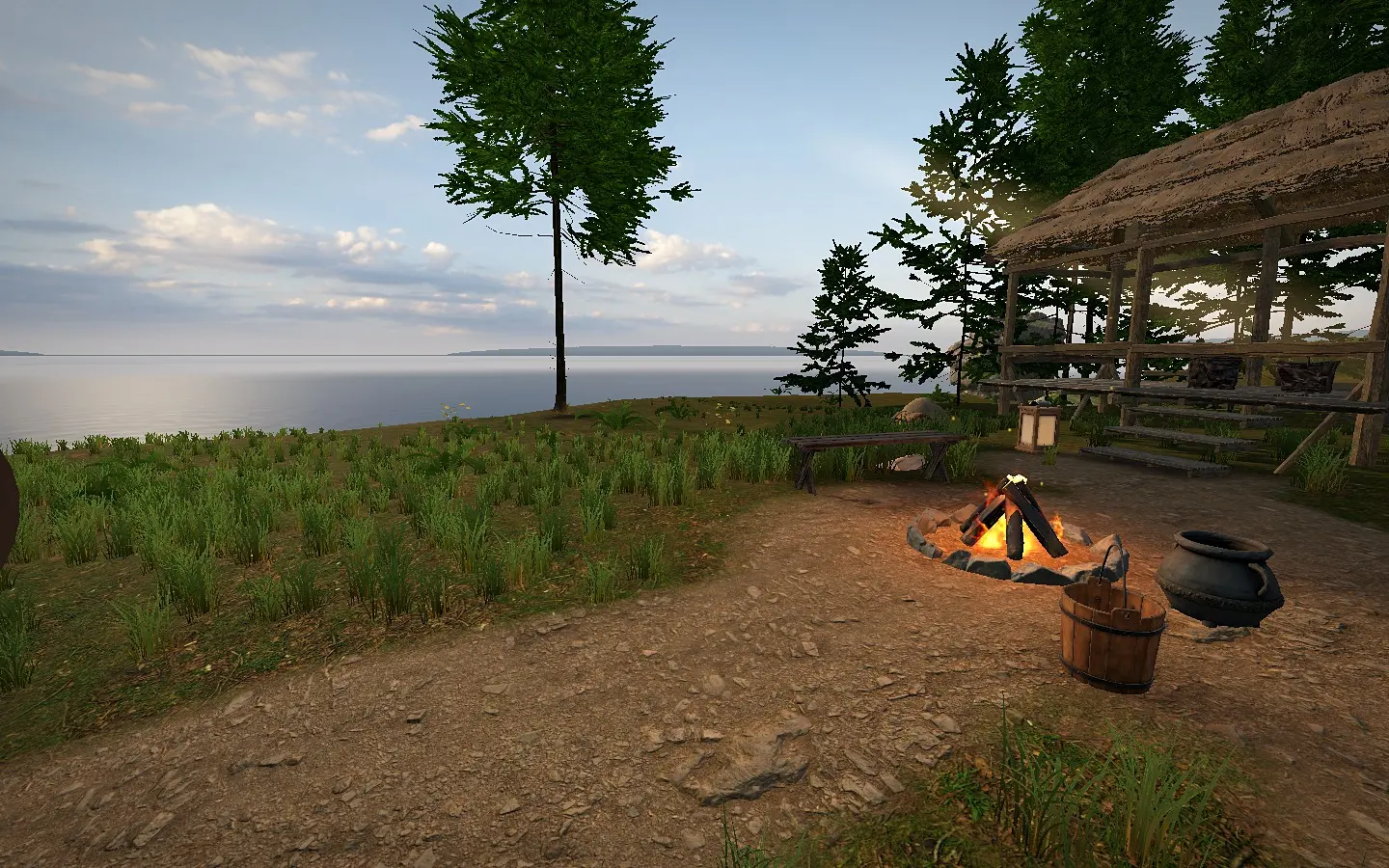 A campfire and cooking pot in the homestead yard beside the shelter.